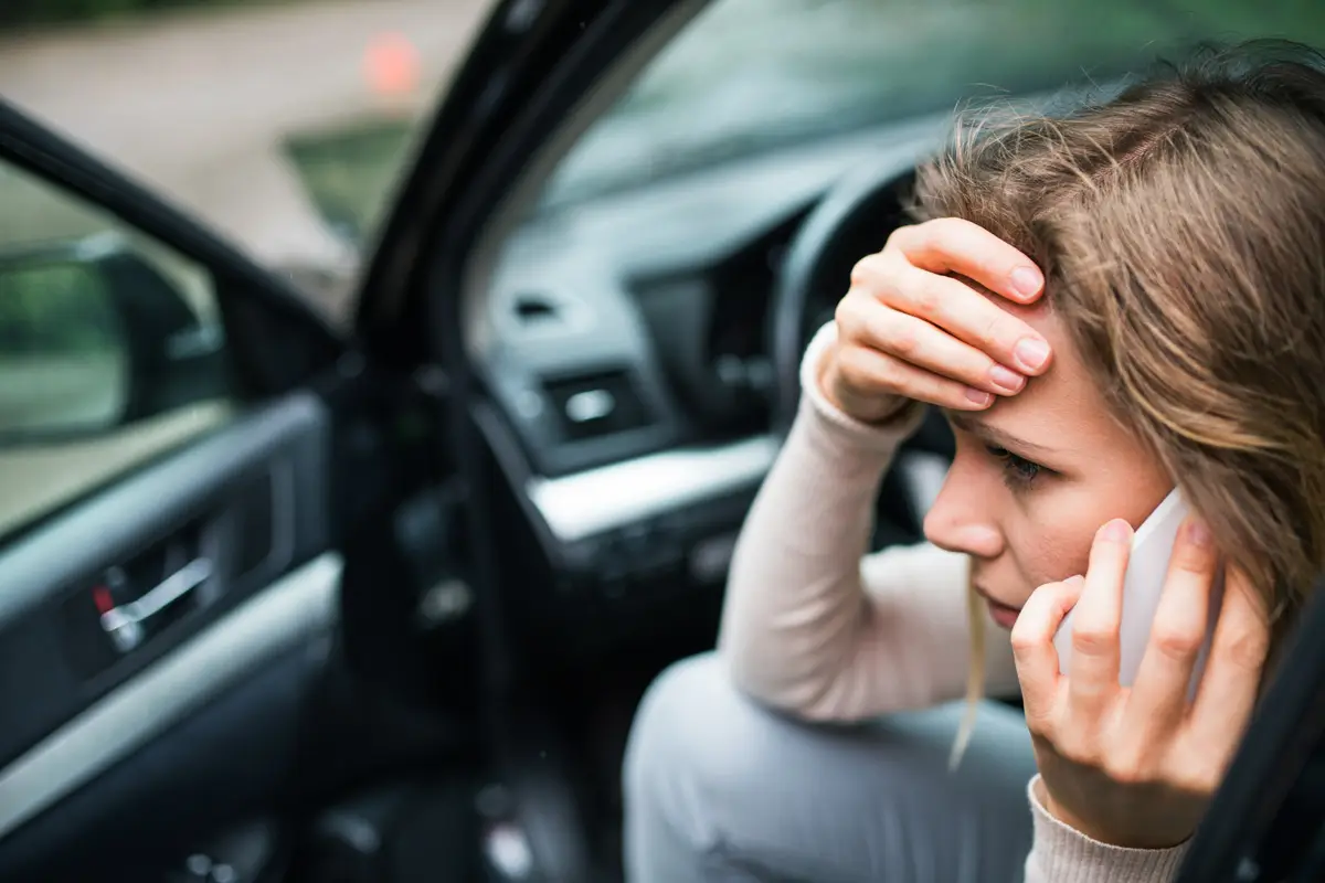 Young woman making a phone call after a car accident